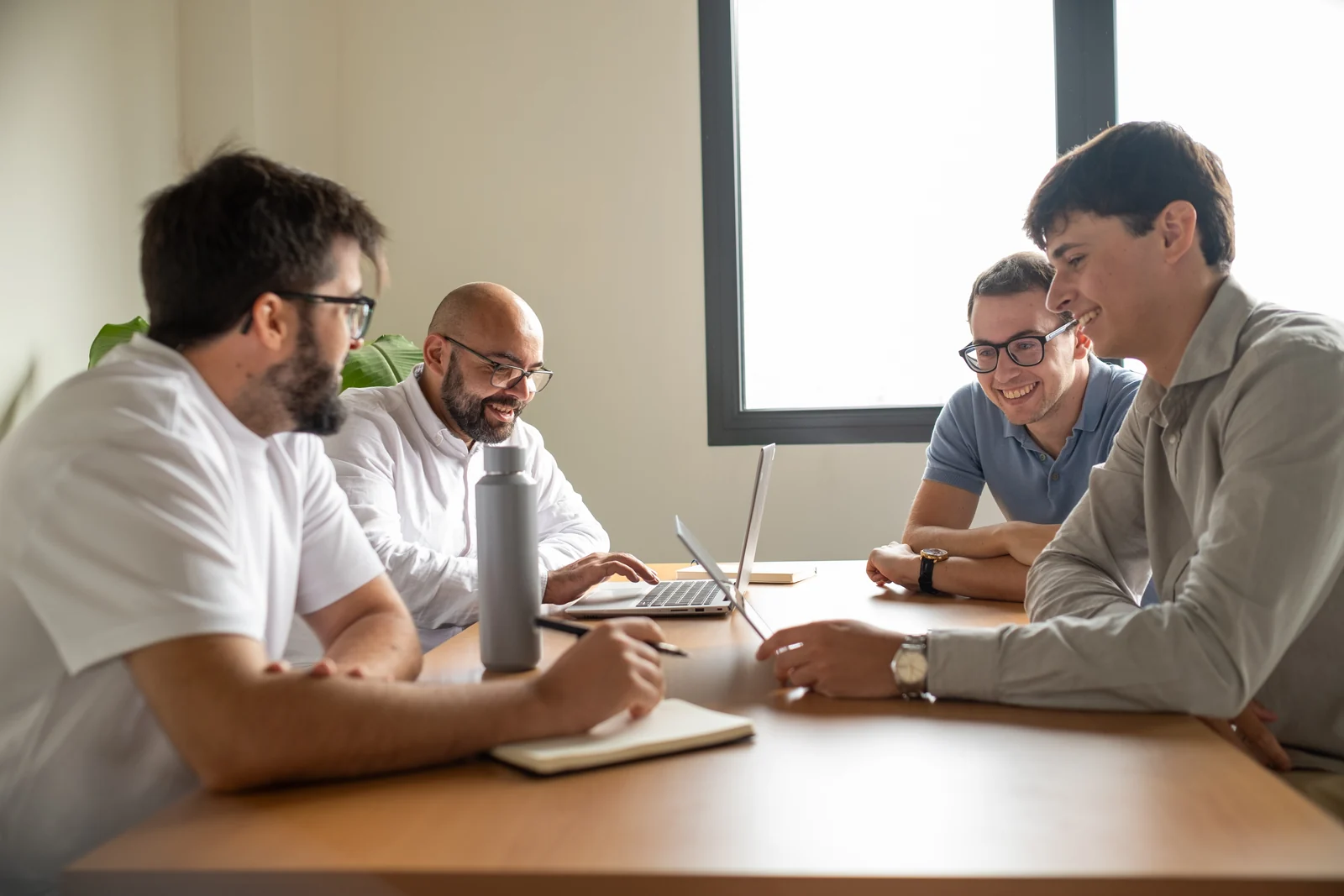 Cuatro compañeros de Lessthan3 compartiendo ideas en una mesa de reuniones