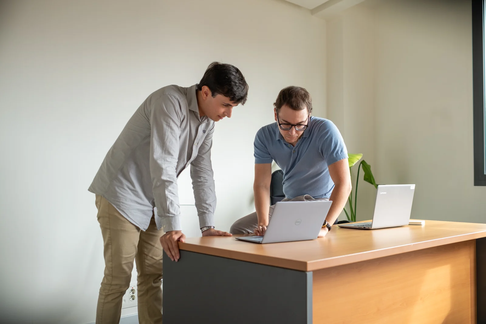 Dos compañeros de Lessthan3 revisando su trabajo en una mesa alta